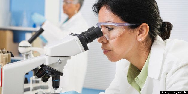 Professional female Hispanic scientist with microscope in laboratory
