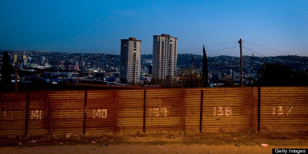 The city of Tijuana, Mexico, stands beyond the U.S.-Mexico border fence in San Diego, California, U.S. on Wednesday, March 21, 2012. Mexico's peso rose, paring its second weekly decline, amid speculation exporters are selling dollars to raise funds for tax payments before a month-end deadline. Photographer: Sam Hodgson/Bloomberg via Getty Images