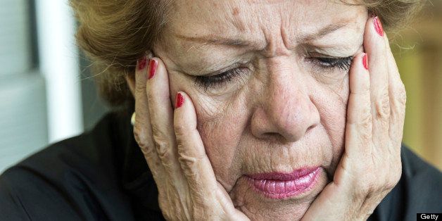 senior woman very frustrated looking down with her hands in her head