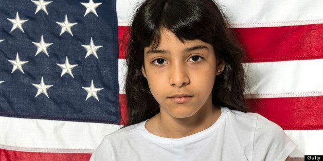 Hispanic little girl posing with the US flag in the background
