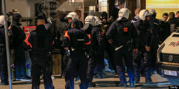 Police officers of the Swedish riot police search young men in the Malarhojden suburb of Stockholm, Sweden on early Saturday