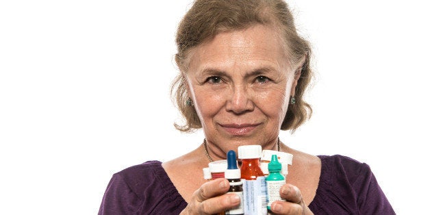 serious senior hispanic woman posing holding her prescription medicines in her hands on white background