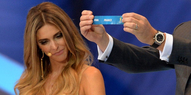 FIFA Secretary General Jerome Valcke shows the name of Belgium next to presenter Fernanda Lima during the final draw of the groups for the Brazil 2014 FIFA World Cup, in Costa do Sauipe, Bahia state, Brazil, on December 6, 2013. AFP PHOTO / NELSON ALMEIDA (Photo credit should read NELSON ALMEIDA/AFP/Getty Images)