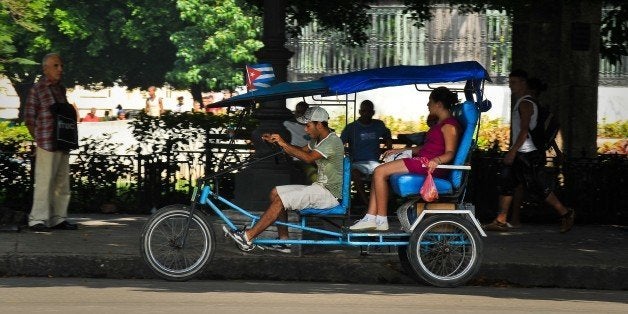 A pedicab carries passengers along a street of Havana, on February 10, 2012. The 50-year-long U.S. embargo to Cuba subjected its people to incredible shortages, but also forced them to find ways to carry on, in which the sociologists call a 'survival culture'. AFP PHOTO/ADALBERTO ROQUE (Photo credit should read ADALBERTO ROQUE/AFP/Getty Images)