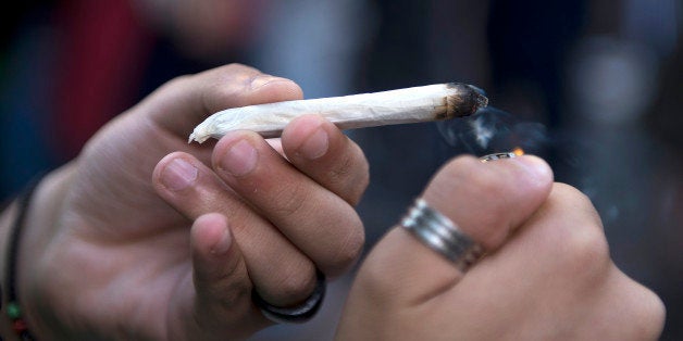 A man lights a joint during a march for the legalization of marijuana towards the Legislative Palace in Montevideo, on December 10, 2013, as the Senate discuss a law on the legalization of marijuana's cultivation and consumption. Uruguays parliament is to vote Tuesday a project that would make the country the first to legalize marijuana, an experiment that seeks to confront drug trafficking. The initiative launched by 78-year-old Uruguayan President Jose Mujica, a former revolutionary leader, would enable the production, distribution and sale of cannabis, self-cultivation and consumer clubs, all under state control. AFP PHOTO/ Pablo PORCIUNCULA (Photo credit should read PABLO PORCIUNCULA/AFP/Getty Images)