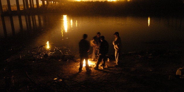 PIEDRAS NEGRAS DEC. 11, 2006 -- Migrants wait along the shore of the Rio Grande River in Piedras Negras, Mexico, Monday, Dec. 11, 2006, with milk jugs full of water used throughout their long journey to the border crossing. They plan to wait for a good time to cross the river into the U.S. Little do they know that they are planing to cross in an area where Border Patrol has started a program called Operation Streamline, where they prosecute all migrants who come into the U.S. illegally. DENVER POST PHOTO BY RJ SANGOSTI (Photo By RJ Sangosti/The Denver Post via Getty Images)