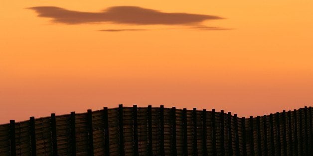 CAMPO, CA - OCTOBER 08: Dusk falls over a section of the US-Mexico border fence which activists opposing illegal immigration hope will be turned into a fully-lit double-fenced barrier between the US (foreground) and Mexico October 8, 2006 near Campo, California. US Fish and Wildlife Service wardens and environmentalists warn that a proposed plan by US lawmakers to construct 700 miles of double fencing along the 2,000-mile US-Mexico border, in an attempt to wall-out illegal immigrants, would also harm rare wildlife. Wildlife experts say cactus-pollinating insects would fly around fence lights, birds that migrate by starlight in the desert wilderness would be confused, and large mammals such as jaguars, Mexican wolves, Sonoran pronghorn antelope, and desert bighorn sheep would be blocked from migrating across the international border, from California to Texas. (Photo by David McNew/Getty Images)