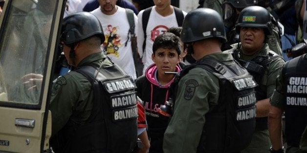 National Guard personnel in riot gear arrest students during an anti-government demonstration in Caracas on May 14, 2014. About 80 demonstrators were arrested during a protest as they request the immediate release of youth detained in recent days. AFP PHOTO/JUAN BARRETO (Photo credit should read JUAN BARRETO/AFP/Getty Images)