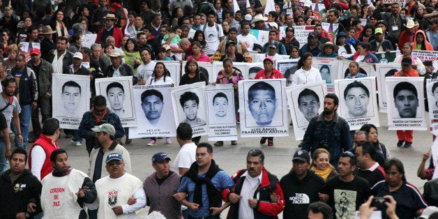 Relatives of the 43 missing students from the Isidro Burgos rural teachers college march holding pictures of their missing loved ones during a protest in Mexico City, Friday, Dec. 26, 2014. Protesters marched through the city to mark the three months since the 43 students were taken by municipal police and then handed over to a drug gang to be killed and then the bodies burned, according to the results of the Attorney General's investigation. (AP Photo/Marco Ugarte)