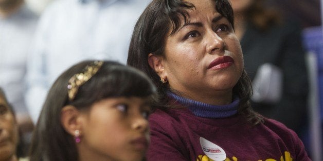 Nancy Catano, 41, a non-US citizen, with her daughter Michelle, 9, watch November 20, 2014 in Los Angeles, California, watch US President Barack Obama's nationally televised announcement on immigration reform. Obama said lifting the threat of expulsion from five million undocumented migrants would make the system 'more fair and just.' AFP PHOTO / Ringo Chiu (Photo credit should read RINGO CHIU/AFP/Getty Images)