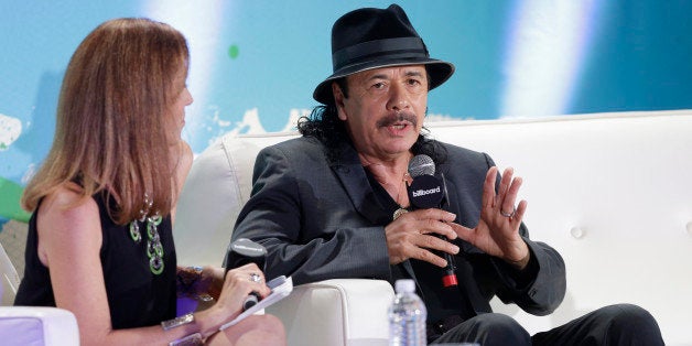 Musician Carlos Santana, right, gestures as he speaks during a question and answer session with interviewer Leila Cobo, left, at the Billboard Latin Music Conference, Wednesday, April 29, 2015, in Miami Beach, Fla. (AP Photo/Wilfredo Lee)