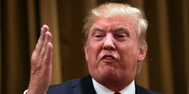 Donald Trump gestures while speaking surrounded by people whose families were victims of illegal immigrants on July 10, 2015