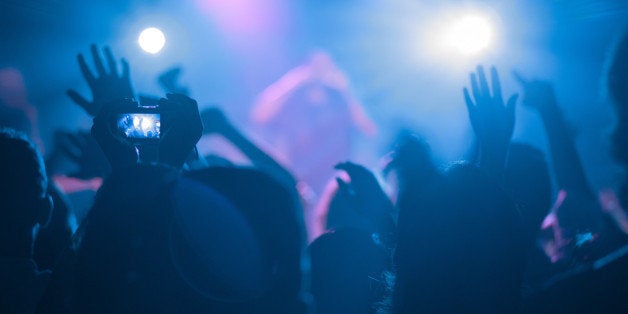 People taking photos and videos of blue and pink lights by camera in rock concert in Austin, Texas.