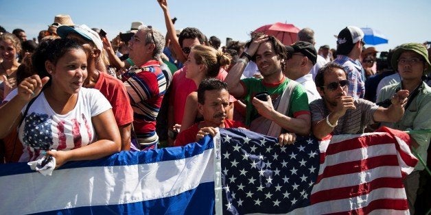 HAVANA, CUBA - AUGUST 14: A Cuban and American flag are trapped over the railing around a crowd of mostly Cubans with some Americans that are gathered to watch the opening ceremony of the Embassy of the United States of America in Havana, Cuba on August 14, 2015. (Photo by Samuel Corum/Anadolu Agency/Getty Images)