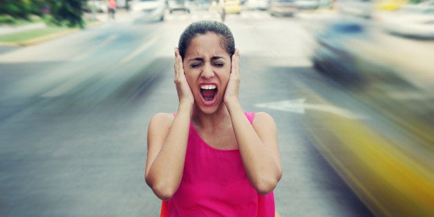 Portrait of woman standing still in the middle of a street with cars passing by fast, screaming stressed and frustrated