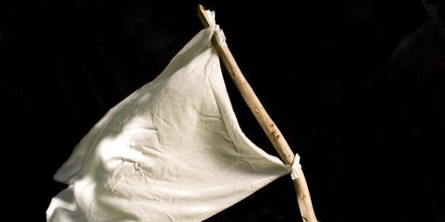 Hands holding and waving a white flag against black background