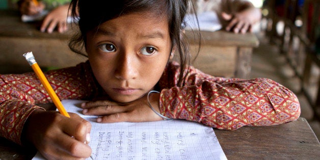 A young Asian girl studies hard her English writing skills (look at what she's writing down).