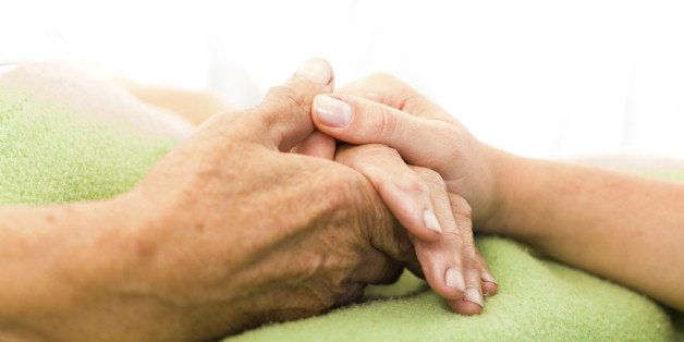 Social services nurse holding elderly woman's hand with care.