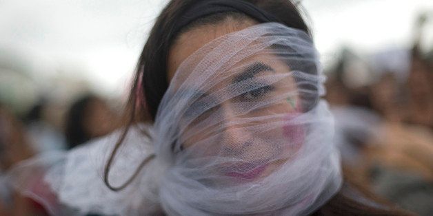 A veiled-face demonstrator chants in mockery; "Women go cook, women go have children," during the "Slutwalk,"an annual protest march against sexual harassment, on Copacabana Beach, in Rio de Janeiro, Brazil, Saturday, Aug. 9, 2014. SlutWalks, sparked by a Toronto police officer's flippant comment that women should avoid dressing like "sluts" to avoid being raped or victimized, have become annual marches in many countries including the U.S., India and Germany, to protest against discrimination and violence against women. (AP Photo/Silvia Izquierdo)