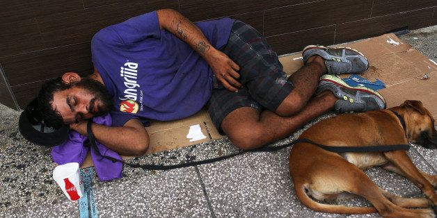 SAN JUAN, PUERTO RICO - JULY 01: A man sleeps on the sidewalk with a dog on July 1, 2015 in San Juan, Puerto Rico. The island's residents are dealing with increasing economic hardships and a financial crisis that has resulted in the government's $72 billion debt. Governor Alejandro Garcia Padilla said in a speech recently that the people will have to sacrifice and share in the responsibilities for pulling the island out of debt. (Photo by Joe Raedle/Getty Images)