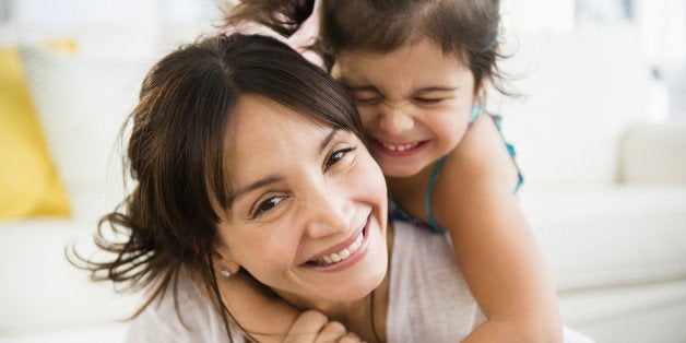 Hispanic mother and daughter playing in living room