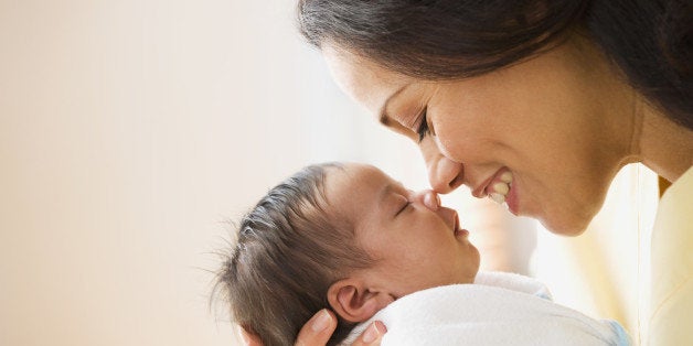 Mother rubbing noses with newborn baby girl