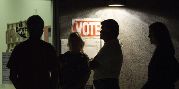 Early morning voters stand in line before sunrise to vote in Arizona's U.S. presidential primary election at a polling statio