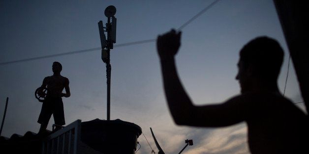Boys watch others flying kites from a rooftop at the Vidigal slum in Rio de Janeiro, Brazil, Friday, Oct. 2, 2015. Despite the recent wave of violence in other pacified favelas, Vidigal has been peaceful and is today a popular tourist spot. (AP Photo/Felipe Dana)