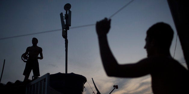Boys watch others flying kites from a rooftop at the Vidigal slum in Rio de Janeiro, Brazil, Friday, Oct. 2, 2015. Despite th