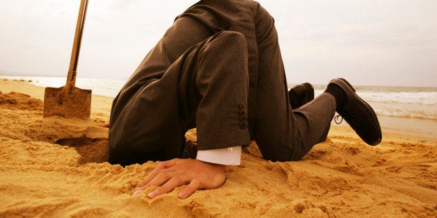 Businessman In Formal Wear Putting Head In Sand