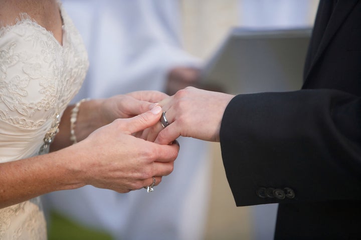 bride putting a ring on groom's ...