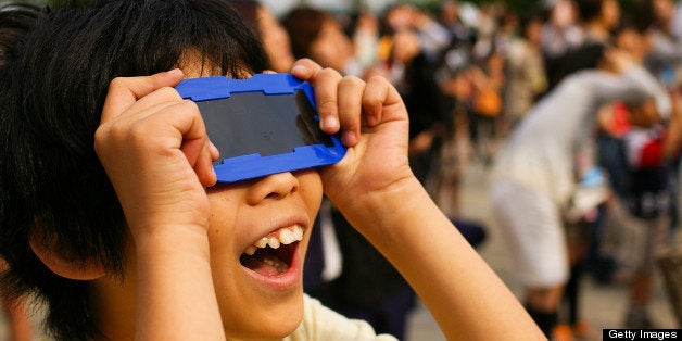 Boy looking at annular solar eclipse with eclipse glasses.