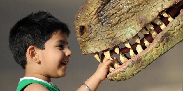 An Indian child plays with a park staff member wearing a dinosaur costume at the Adlabs Imagica theme park at Sangewadi some 100 kms south-east of Mumbai on April 20, 2013. India's most elaborate theme park opened this week with special-effect Hindu gods and Bollywood-themed rides, aiming to tap a thirst for family entertainment among the country's rising middle-class. Adlabs Imagica, which cost about USD 294 million to create, opened its doors to the public on Thursday between the western cities of Mumbai and Pune, with capacity for 10,000 to 15,000 visitors a day. AFP PHOTO/ INDRANIL MUKHERJEE (Photo credit should read INDRANIL MUKHERJEE/AFP/Getty Images)