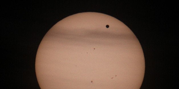 Planet Venus (R-black spot) transits in front of the Sun seen from the the Urania observatory, in Vienna on June 6, 2012. Astronomers and novice star-gazers worldwide trained their eyes and telescopes on the skies Wednesday for the last chance this lifetime to observe Venus track a near seven-hour path across the Sun. The event, only to be seen again in 105 years, began shortly after 2200 GMT on Tuesday, visible first from the Pacific and north and central Americas as a small black dot trailing across the solar surface. AFP PHOTO / ALEXANDER KLEIN (Photo credit should read ALEXANDER KLEIN/AFP/GettyImages)