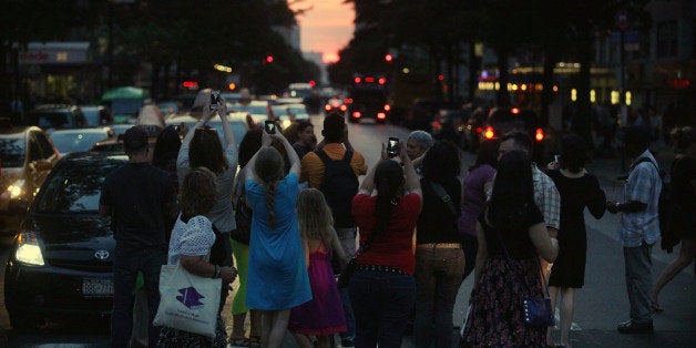 NEW YORK, NY - MAY 29: People watch and photograph the sunset on 14th Street during 'Manhattanhenge' on May 29, 2013 in New York City. This semiannual occurrence happens each summer when the setting sun aligns east-west with the street grid of the city. (Photo by Mario Tama/Getty Images)