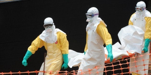 Staff of the 'Doctors without Borders' ('Medecin sans frontieres') medical aid organisation carry the body of a person killed by viral haemorrhagic fever, at a center for victims of the Ebola virus in Guekedou, on April 1, 2014. The viral haemorrhagic fever epidemic raging in Guinea is caused by several viruses which have similar symptoms -- the deadliest and most feared of which is Ebola. AFP PHOTO / SEYLLOU (Photo credit should read SEYLLOU/AFP/Getty Images)