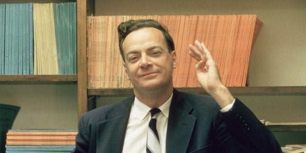 1959: American physicist Richard Feynman (1918 - 1988) stands and raises one hand, in front of some shelves at Cal Tech University, Sacramento, California. (Photo by Joe Munroe/Hulton Archive/Getty Images)