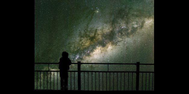 A child looks into space and the Milky way. Long exposure photograph from an astronomical observatory site.