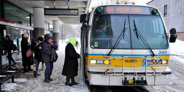 Passengers board a bus outside the MBTA subway stop in Davis Square in Somerville, Mass., Tuesday, Feb. 10, 2015. The third major winter storm in two weeks left the Boston area with another two feet of snow and forced the MBTA to suspend all rail service for the day. (AP Photo/Josh Reynolds)