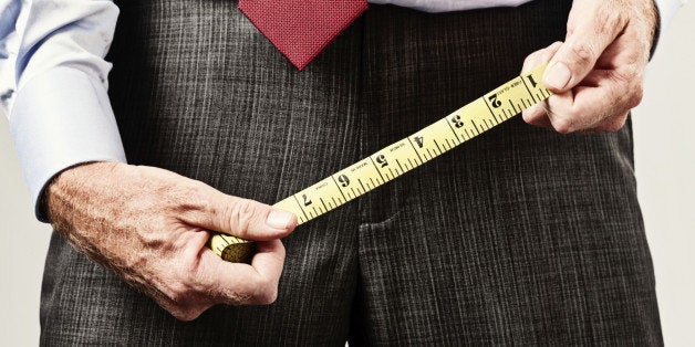 Cropped shot of a man holding a tape measure over his pelvis, apparently checking to see whether his penis size measures up!