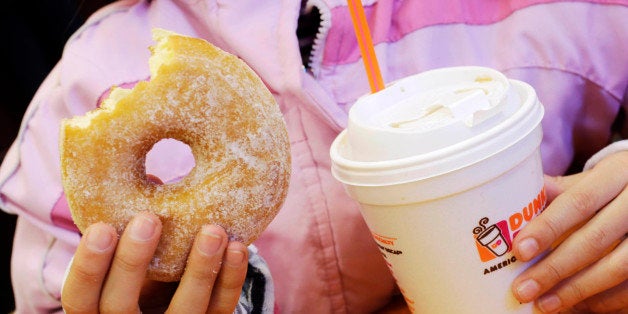 FILE - In this Feb. 14, 2013 file photo, a girl holds a beverage, served in a foam cup, and a donut at a Dunkin' Donuts in New York. The New York City Council's sanitation committee has a hearing set for Monday, Nov. 25, 2013, on proposals to ban plastic-foam food containers or explore recycling them. (AP Photo/Mark Lennihan, File)