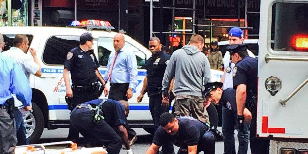 Medical technicians tend to David Baril, who was shot and wounded by police after he pulled a hammer from a bag and lunged at officers who approached him on the street near New York's Penn Station on Wednesday, May 13, 2015. Baril, 30, is suspected of attacking four people with a hammer earlier in the week. (AP Photo/Raj Mathura)