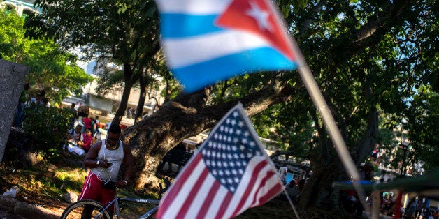 A man chats on his mobile phone, close to a pair of Cuban and US flags strapped to a bicycle taxi, at a public Wi-Fi hotspot in Havana, Cuba, Wednesday, Aug. 12, 2015. The US embassy in Cuba will hold a ceremony on Friday, Aug. 14, to raise the U.S. flag, to mark its reopening on Havanaâs historic waterfront. (AP Photo/Ramon Espinosa)