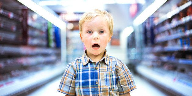 Young boy standing in middle of a supermarket aisle screaming and looking scared.