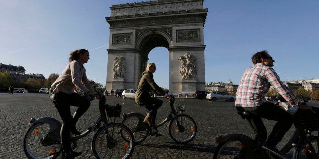 Tourists enjoy bicycle tours pass the Arch of Triumph in the Champs Elysees district of Paris, France, Sunday, Nov. 15, 2015. Thousands of French troops deployed around Paris on Sunday and tourist sites stood shuttered in one of the most visited cities on Earth while investigators questioned the relatives of a suspected suicide bomber involved in the country's deadliest violence since World War II. (AP Photo/Amr Nabil)