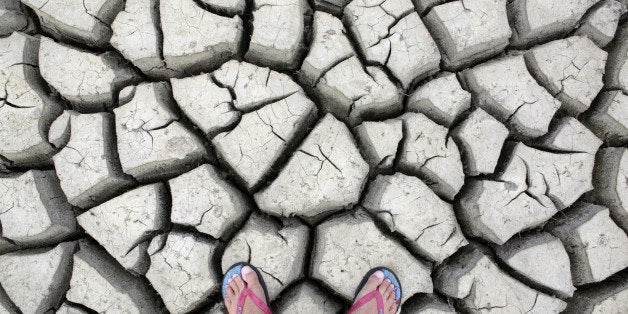 Large cracks in rock hard earth of water hole during dry season drought.