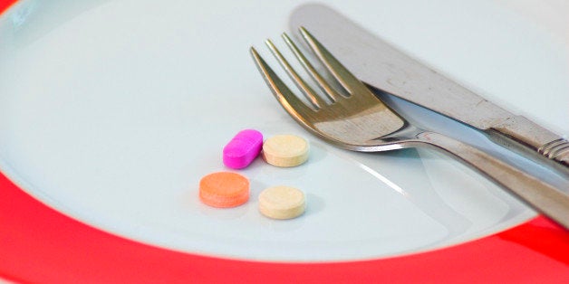 4 colourful pills to be eaten with a fork and knife, instead of food. A cinceptual image for eating disorder and over use of food additives, vitamins and diet drugs