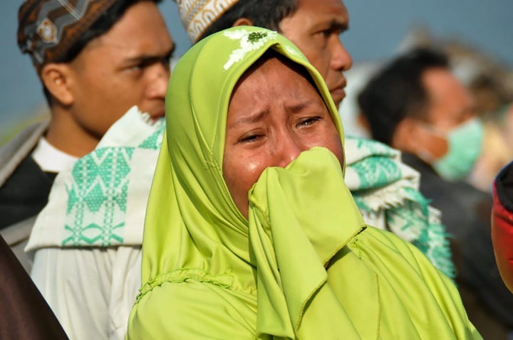 A woman cries as people look at the damages after an earthquake and a tsunami hit Palu, on Sulawesi island on September 29, 2018.