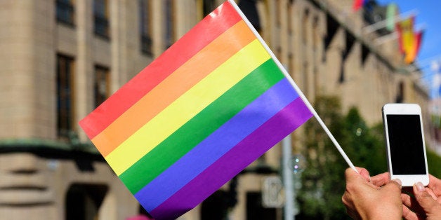 Pride flag and spectator taking pictures with mobile phone