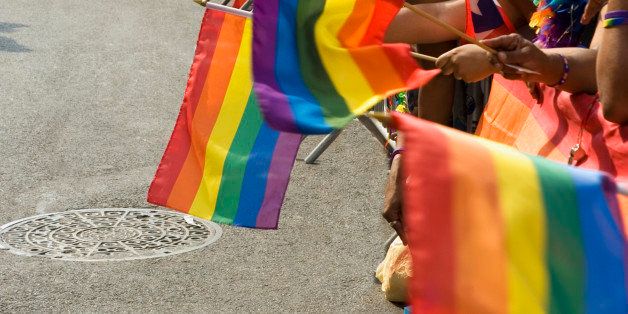 Rows of hands holding gay pride, rainbow-colored flags, close-up